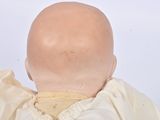 a doll with a bald head wearing a white dress