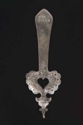 an old silver spoon with a handle on a black background