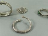 trois bagues en argent et une bague sertie de pierres vertes posées sur une table