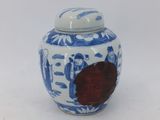 un petit pot bleu et blanc orné d'une fleur rouge