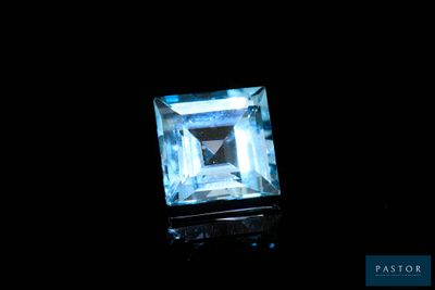 Une pierre de topaze bleu aqua est mise en valeur dans l'obscurité