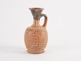 a small brown vase with a handle on a white surface