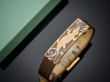 leather bracelet with gold and brown design on it next to a green box