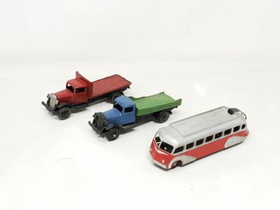 three toy trains and a bus on a white surface