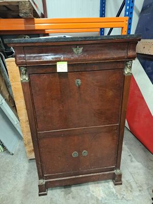 une commode en bois dans une pièce où se trouve un drapeau