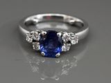un gros plan d'une bague en saphir bleu et diamants posée sur une table
