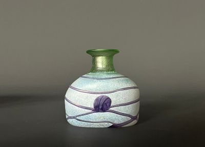 un vase vert posé sur une table sur fond noir