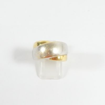 gros plan d'une bague en or et en argent sur une surface blanche