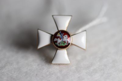 a small white cross with a red and green flower on it