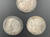 three different types of silver coins on a black surface
