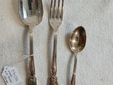 trois cuillères en argent et deux cuillères en argent posées sur une nappe blanche