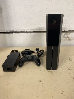 La Xbox One est posée à côté d'une manette de jeu et d'un chargeur