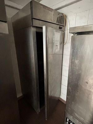 un réfrigérateur argenté au milieu d'une pièce sale
