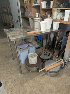 many buckets and pans sitting on a table in a garage