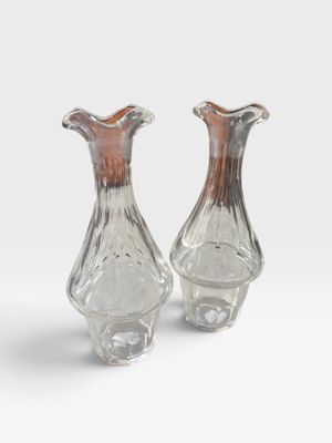 une paire de vases en verre posés sur une surface blanche, avec un fond blanc