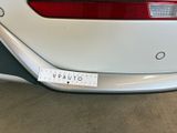 the rear end of a white car with a sticker on it ' s bumper