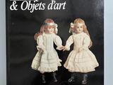 un livre ancien posé sur une table, dans lequel se trouvent deux poupées