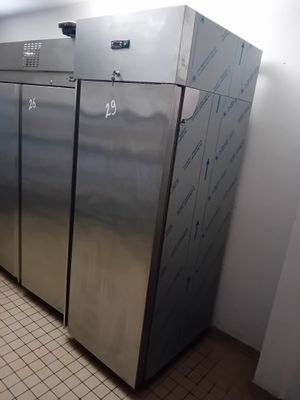 Plusieurs réfrigérateurs en acier inoxydable sont alignés contre un mur