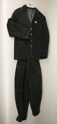 une photo d'un costume noir et d'un pantalon suspendus à un mur