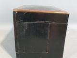 an old black box with a wooden top sitting on top of a white surface