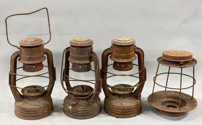 four old fashioned oil lamps are lined up on a white surface