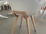 a white chair with wooden legs in the middle of a room