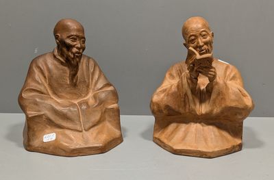 deux figurines représentant des vieillards assis sur une table, sur fond gris