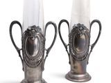 two silver vases sitting next to each other on a white surface