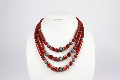 un collier composé de perles rouges et d'argent sur un mannequin blanc