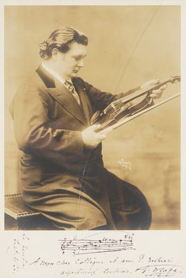 an old photo of a man in a suit and tie holding a rifle