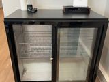 un petit réfrigérateur posé au sol, muni de deux portes en verre