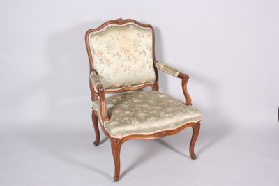 une chaise dont le dossier est recouvert d'un tissu à motifs floraux et dont la structure est en bois