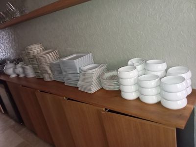 a lot of plates and cups on a wooden shelf