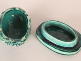 pair of green ceramic bowls with oval handles on a white surface