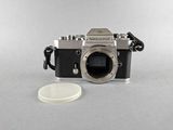 a silver camera and a white coin on a table
