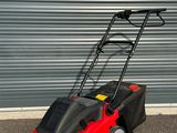 une photo d'une tondeuse à gazon rouge garée devant la porte d'un garage