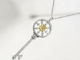 Pendentif en forme de clé en argent et diamants jaunes, avec chaîne, sur fond blanc