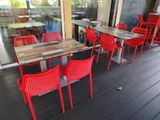many red chairs and tables on the deck of a restaurant