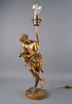 une statue en or représentant un homme tenant une ampoule posée sur une table