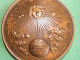a bronze medal with a sun and clouds on it