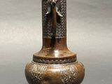 a bronze vase with a bird on it on a stand