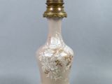 un vase blanc et doré posé sur un socle surmonté d'une lampe