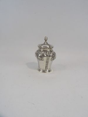 un petit vase en argent posé sur une surface blanche, sur fond blanc