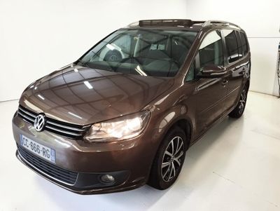 La camionnette marron est garée dans une pièce blanche, à côté d'autres voitures.