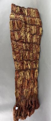 un objet tricoté de couleur marron posé sur une surface blanche