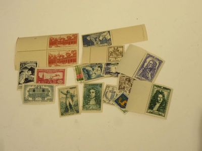 de nombreux timbres différents posés sur une table, à côté d'une feuille de papier