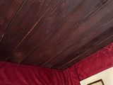 a bed in a room with red curtains and a wooden headboard