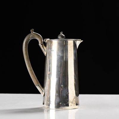 a silver coffee pot sitting on a table with a black background