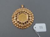an image of a gold pendant with a coin in the center
