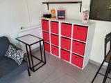 a room with a couch, a table, and a shelf with red bins on it